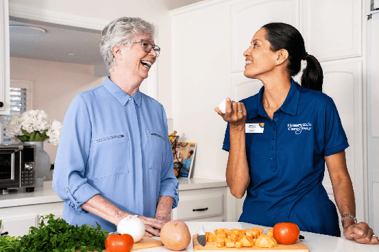 A HomewatchConnect caregiver and her client laughing together in a Houston kitchen